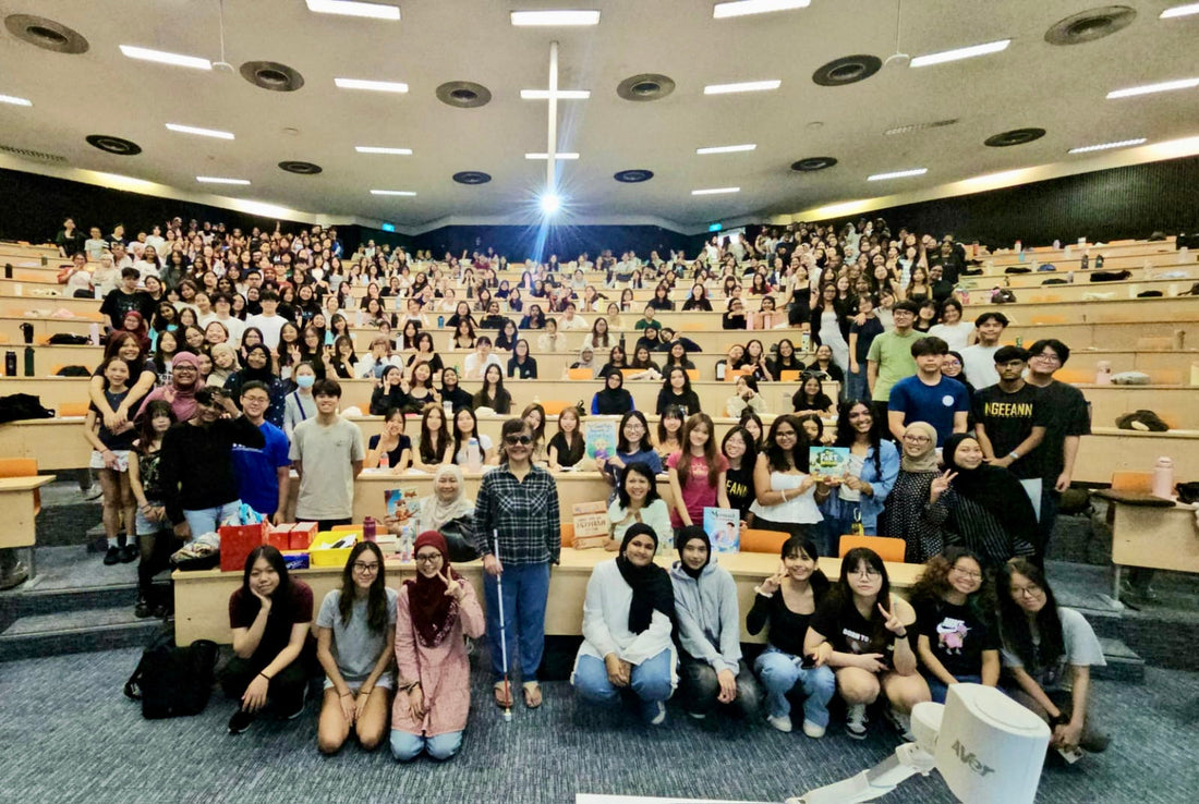Author Sherri Eri stands with a large crowd of approximately 450 Ngee Ann Polytechnic students in an auditorium for a commemorative group photograph.